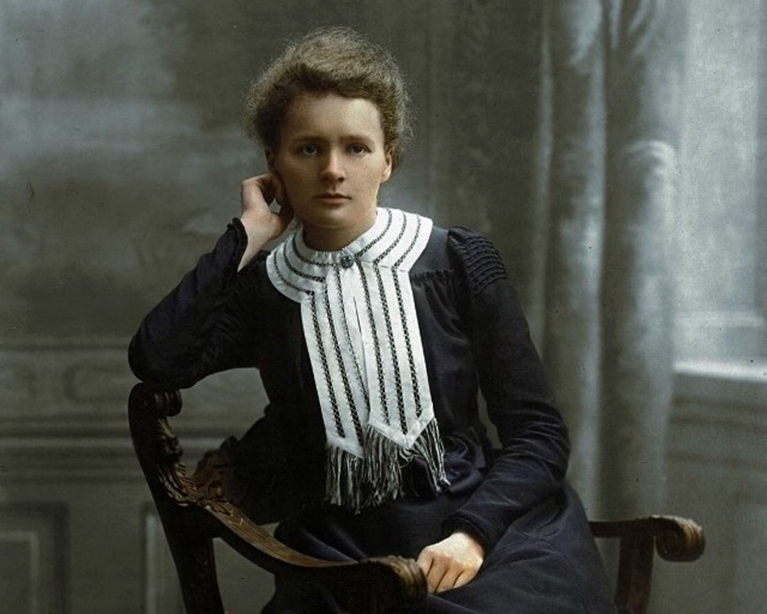 Young Marie Curie sitting in a thoughtful pose, dressed in a dark dress with a white collar, early portrait.