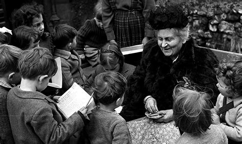 An older Maria Montessori engaging with a group of young children, sharing her educational philosophy.