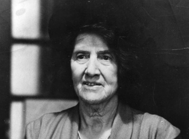 Black and white photograph of an older Marie Charlotte Carmichael Stopes wearing a hat, capturing her later years in life.